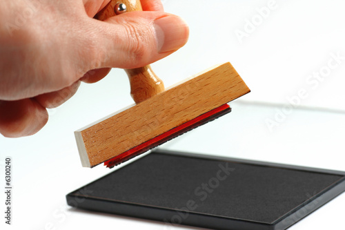 Hand mit Stempel vor Stempelkissen