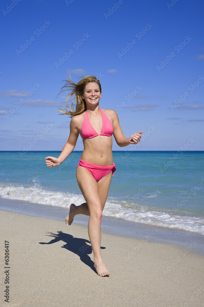 Beautiful Caucasian female teenage running through to surf 