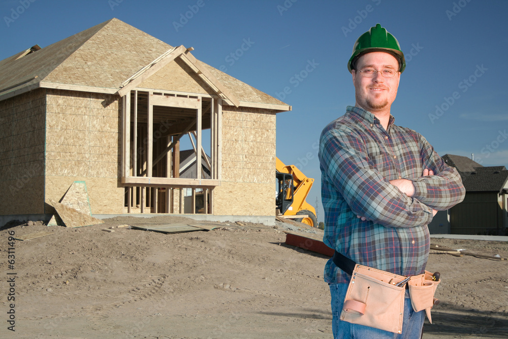 Construction worker standing in front of a new home Construction worker standing in front of a new home