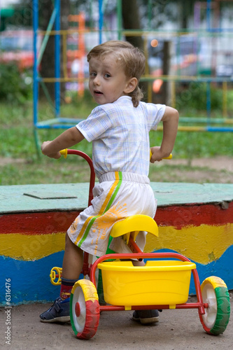 The little boy sits on a bicycle and looks back