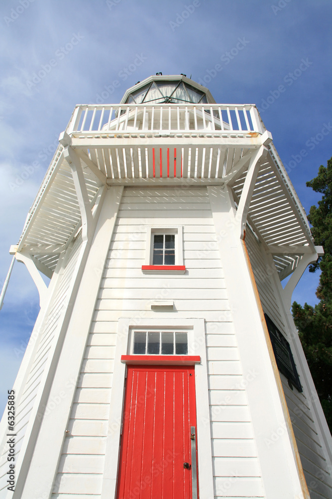 Looking up at a white wooden lighthouse