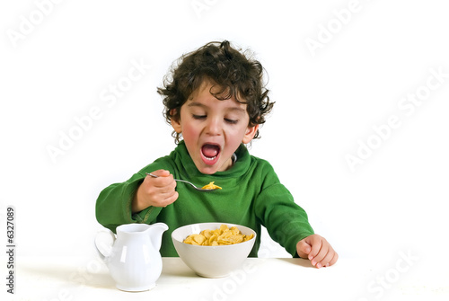 young boy eating cornflakes isolated on white