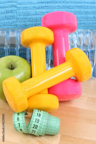 sports equipment - dumbbells water and green apple
