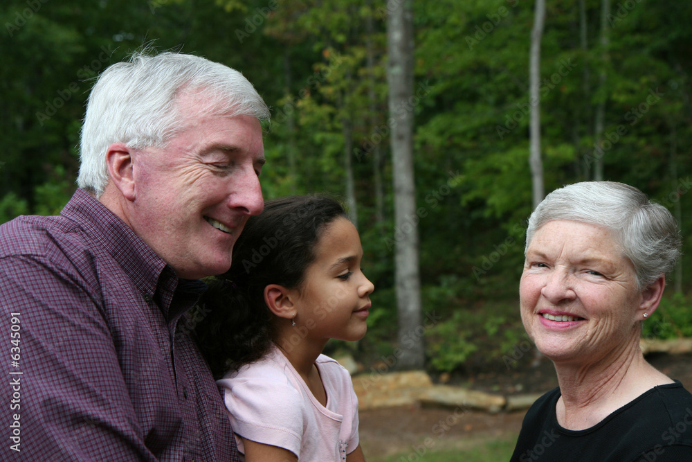 Happy Senior Couple smiling outside with grandchild Happy Senior Couple smiling outside with grandchild