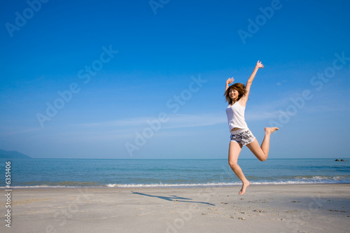 woman jumping happily having fun by the beach
