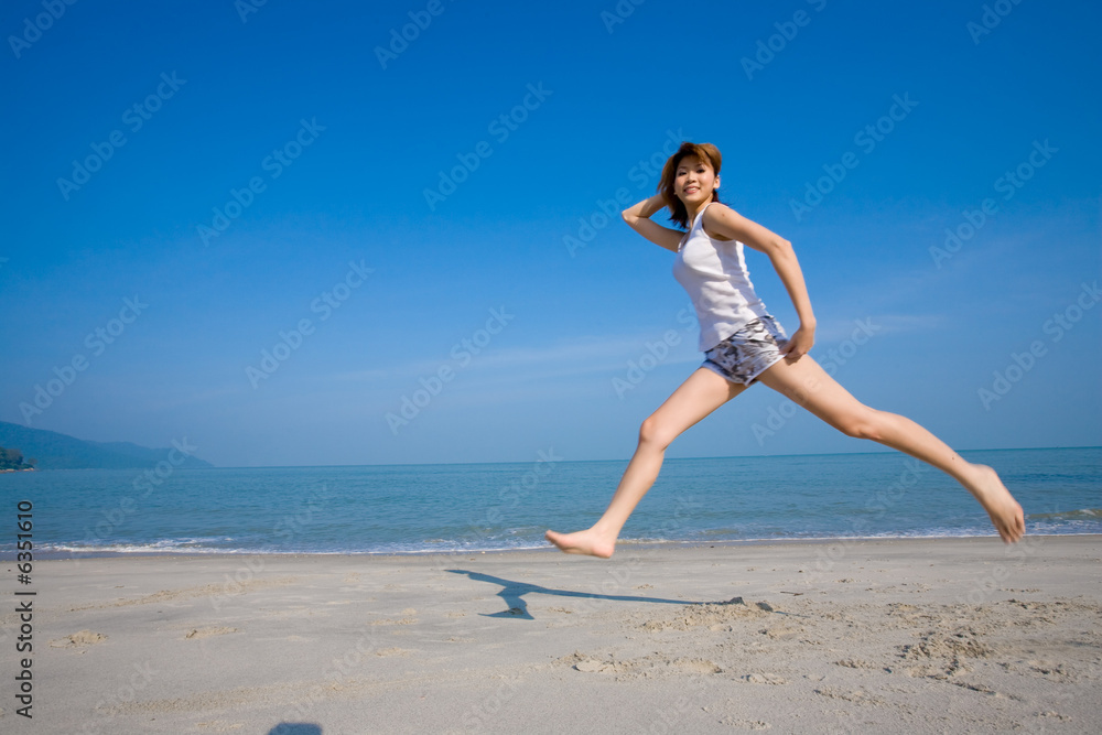 woman wide leaping on a beautiful day at the beach