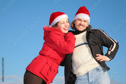 couple against blue sky background in winter in santa claus hats