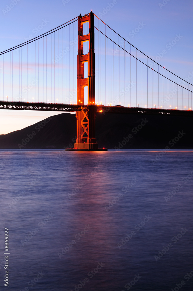Fototapeta premium Southern tower of Golden Gate Bridge glows at sunset 