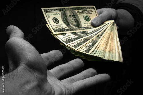 A stack of cash being handed in partial color