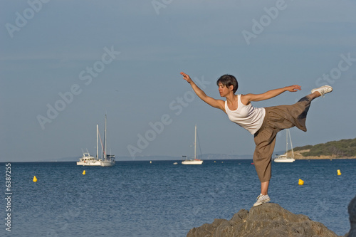 Woman making a exercise of balance at the seaside