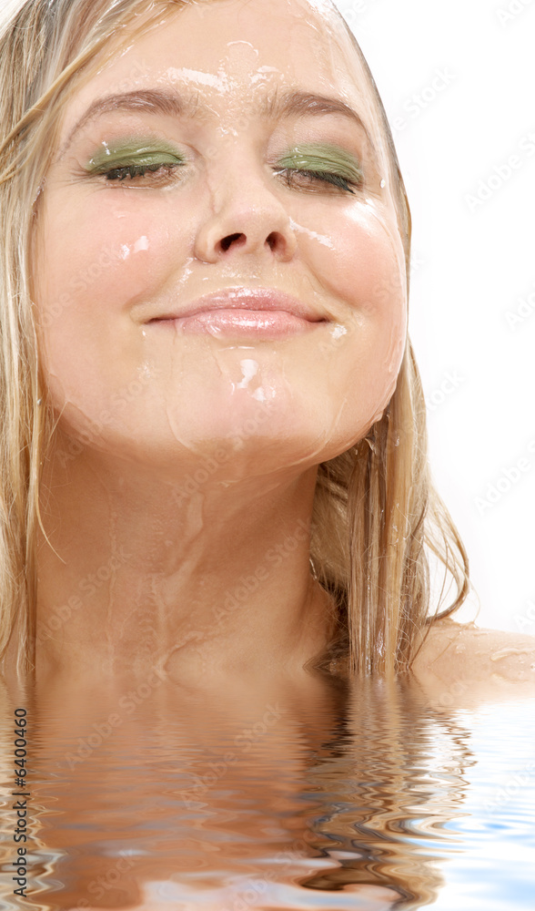 Naklejka premium portrait of happy blond washing face in water