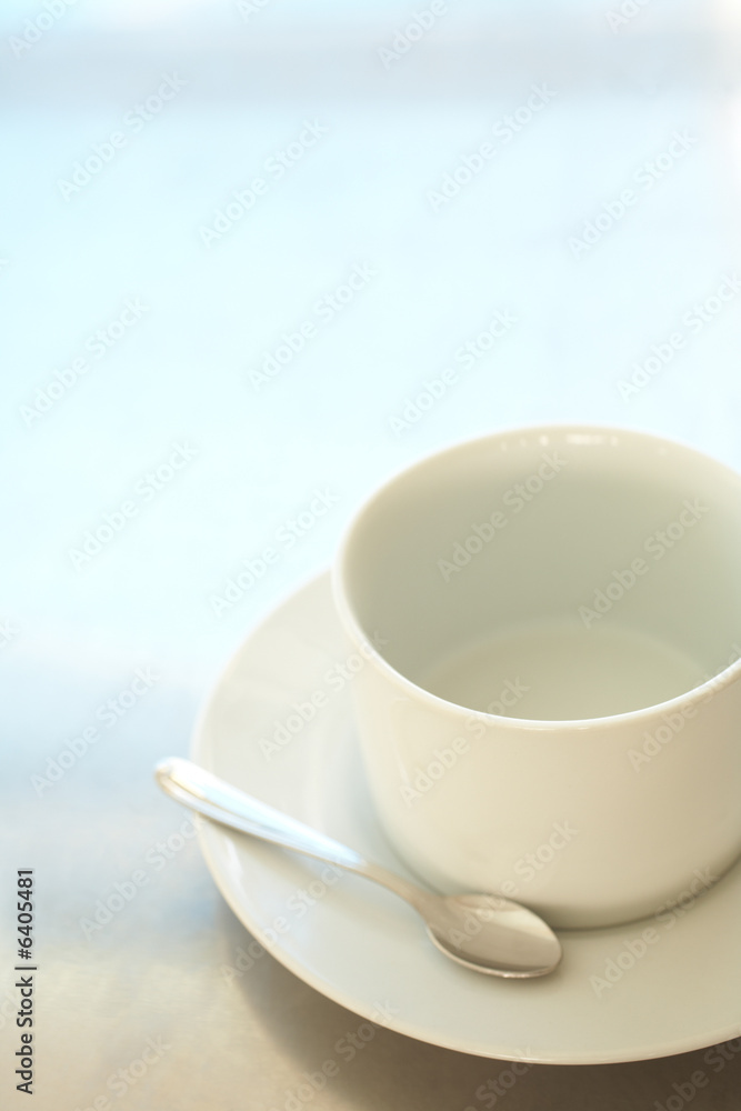 Empty white ceramic coffee cup and silver teaspoon Empty white ceramic coffee cup and silver teaspoon
