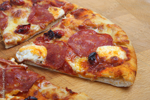 Sliced pizza with salami  cheese and sun-dried tomatoes