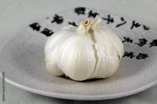 Isolated, white, fresh garlic on ceramic, small plate on white