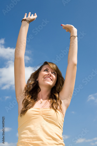 Beautiful teen girl raising her arms in praise or worship. 