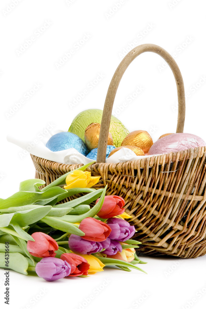 Basket of chocolate easter eggs with a bunch of fresh tulips
