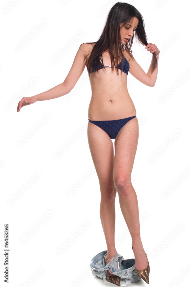 Foto de A young sexy adult girl in bikini take off shorts do Stock