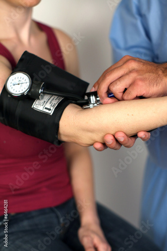 Medical worker checking woman's blood pressure
