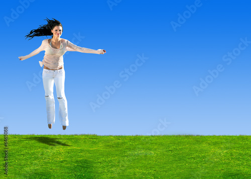 Woman jumping on a hill of green grass