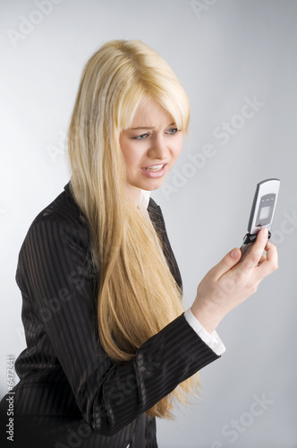 cute blond woman in formal dress looking at her mobile