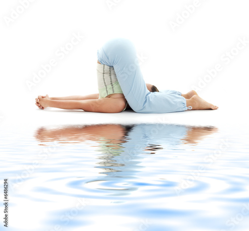 sporty girl practicing halasana plow pose on white sand photo