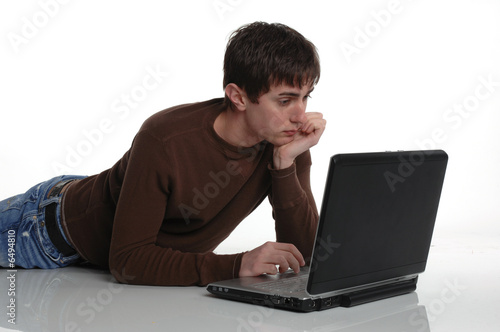 young male lying down with laptop computer reflecting