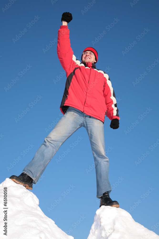 man in red jacket on top of snow hill with hand up man in red jacket on top of snow hill with hand up