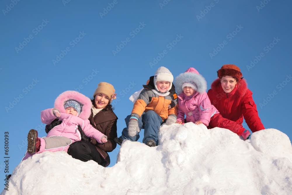 two mothers with child sit on snow hill