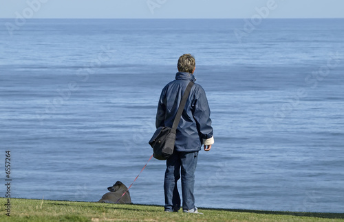 Mujer con perro mirando al mar