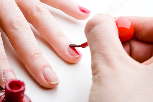 Finger diagonal beim Lackieren mit rotem Nagellack