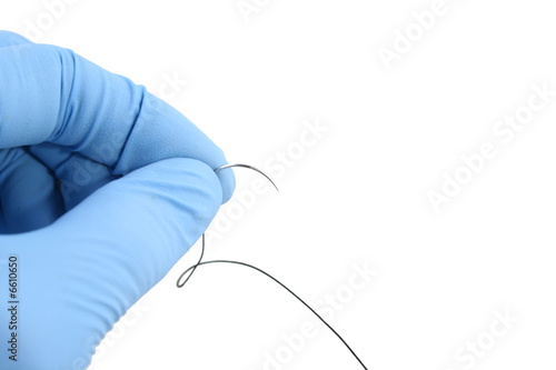 gloved hand holding suture needle