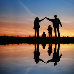 silhouette family house on sunset water