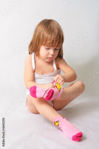 Small girl is puting on the socks