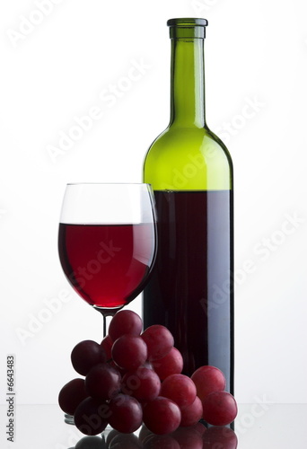 Glass of red wine with bottle and grapes