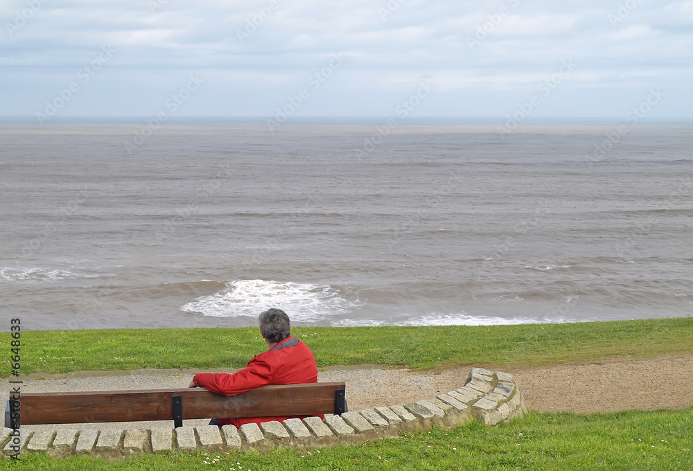 Hombre sentado en un banco mirando al mar