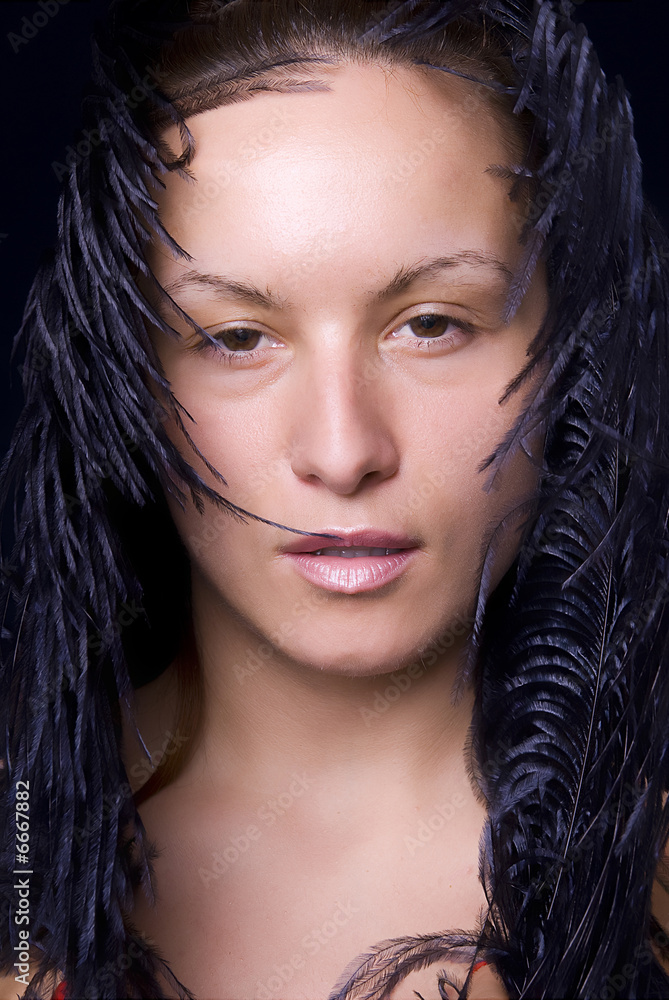 Beautiful womans face hiding in feathers Beautiful womans face hiding in feathers