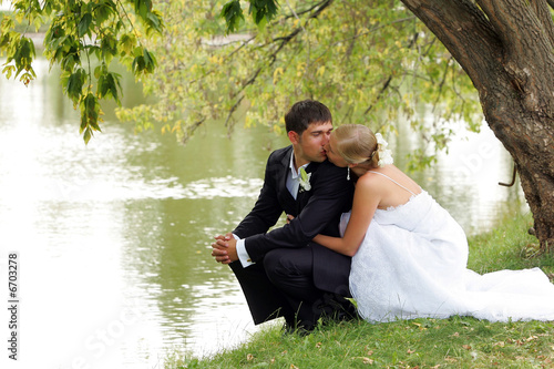 Newlywed couple kissing by lake