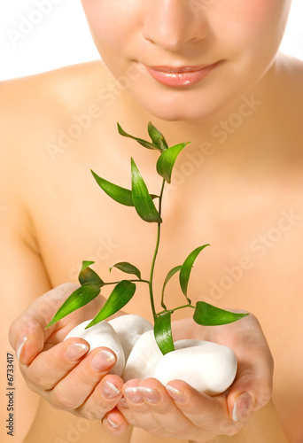 Fotografie Beautiful blond girl holding young plant growing up through ston