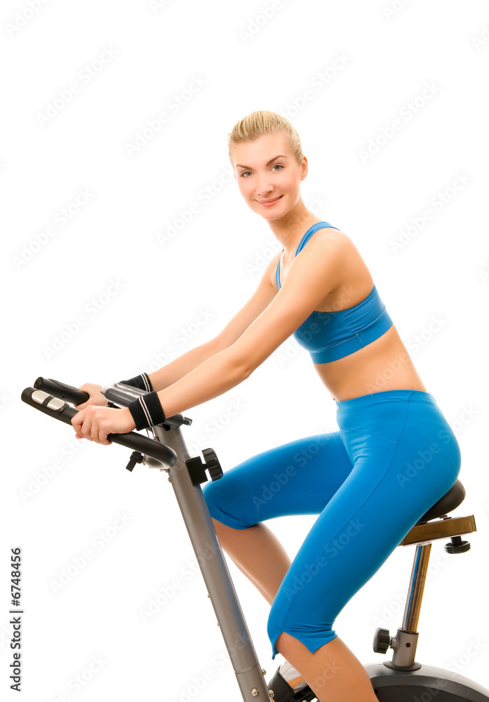 Beautiful young woman on exercise bicycle over white background Beautiful young woman on exercise bicycle over white background