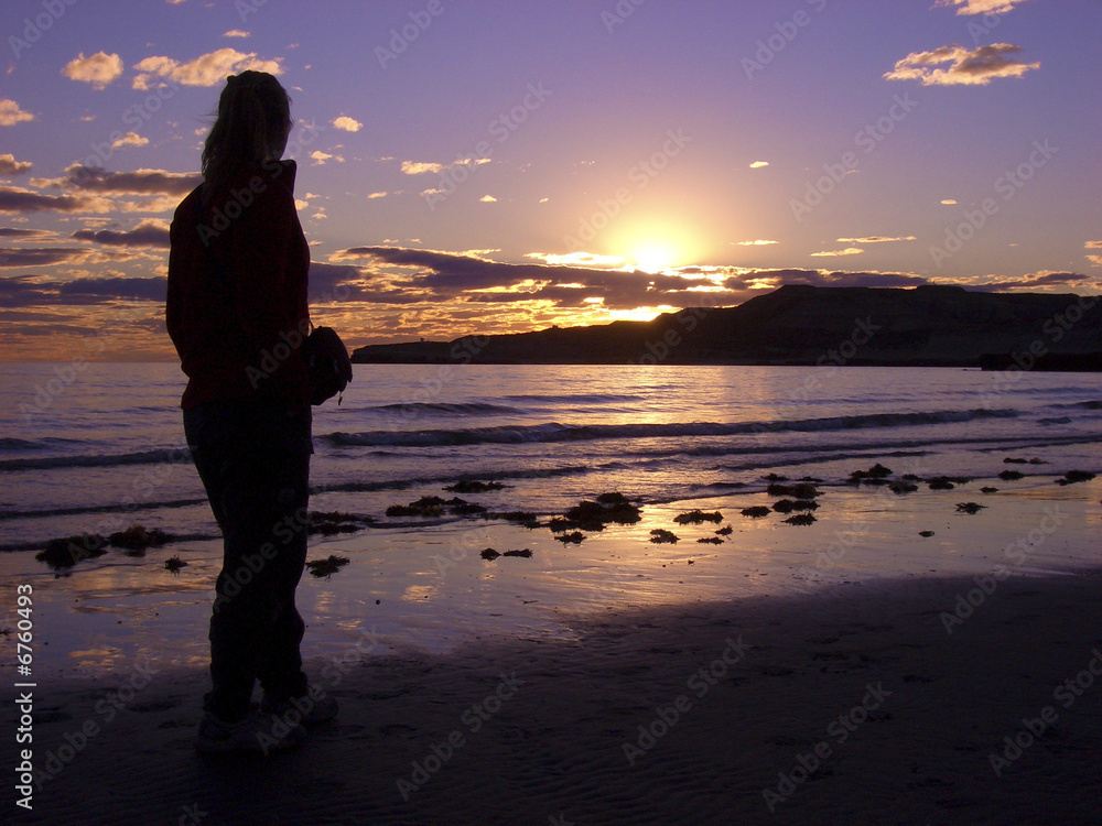Frau am Strand schaut in den Sonnenuntergang