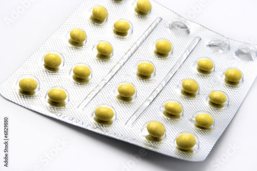 Yellow pills in silver package on white background