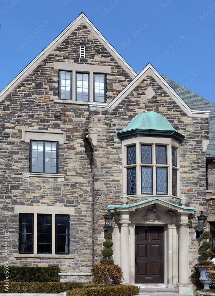 stone house with portico entrance and oriel window