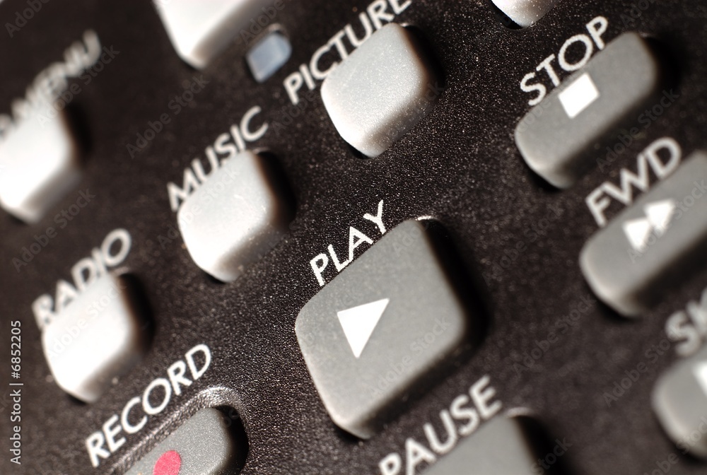 A closeup of a remote control focusing on the play button. A closeup of a remote control focusing on the play button.