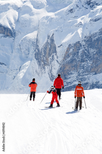 Family on slope. Rocky mountains in background.