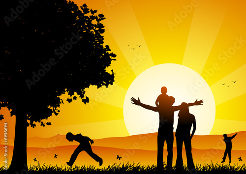 Happy family at sunset under a tree