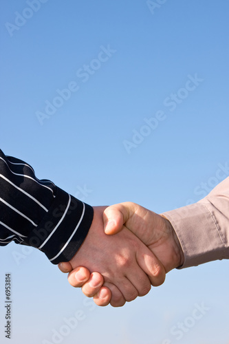 Two people doing handshake on blue sky bacground