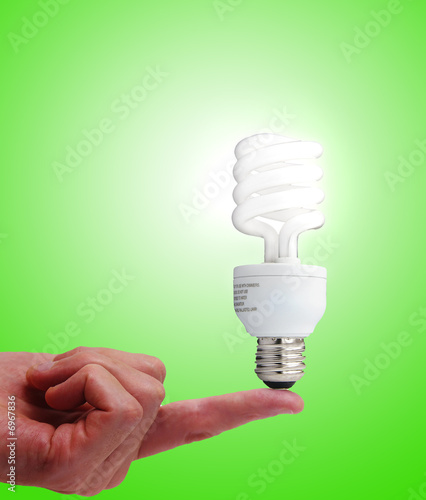 Compact fluorescent bulb on a finger, on green