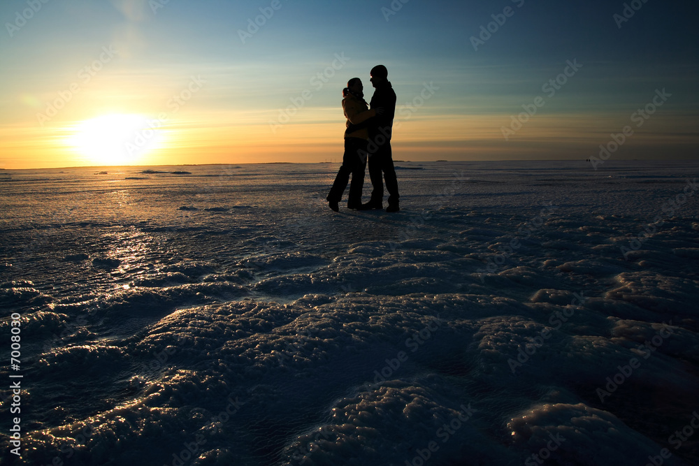Couple holding hands against sunset on frozen sea