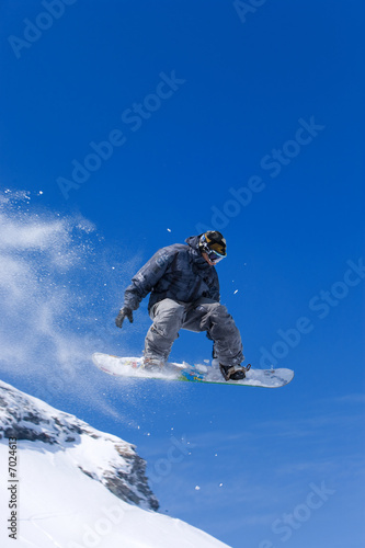 Male snowboarder jumping of a hill