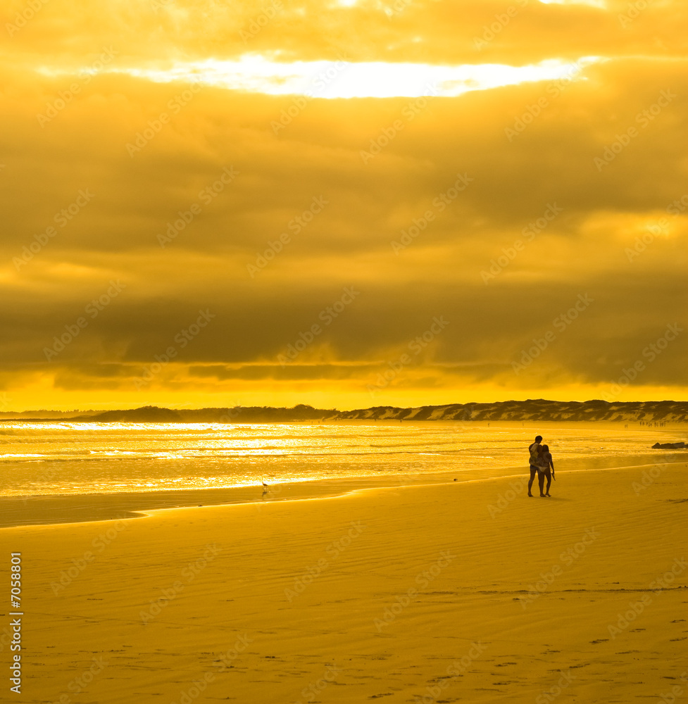 young couple walking in sunset beach